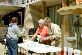 Carol Moser (red sweater) and Carol Schultz setting up the Drizzle sales display table.